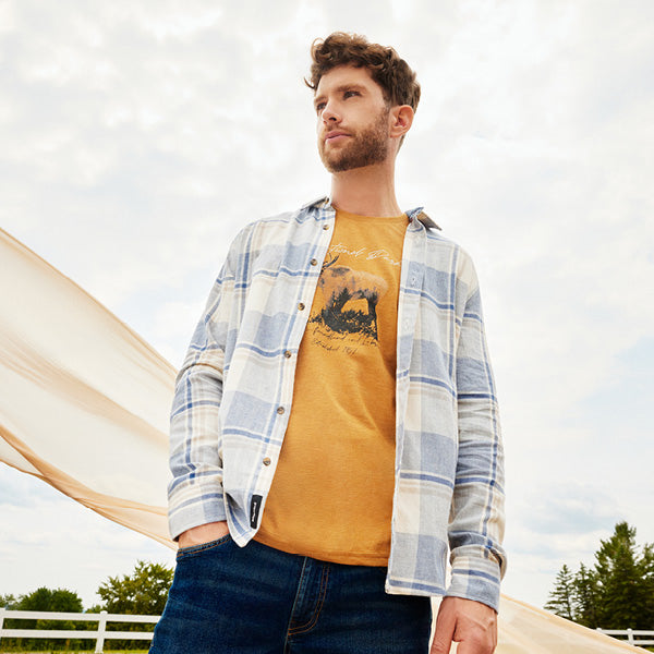 Homme portant un ensemble de vêtements décontractés, jean, t-shirt et chemise.